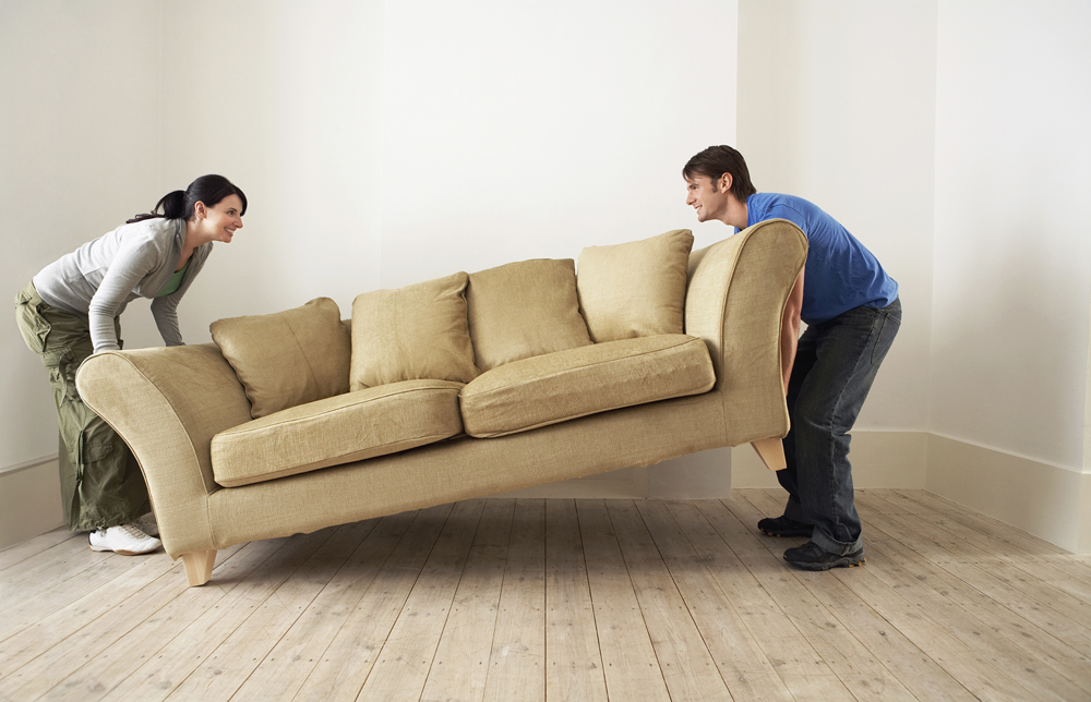 Couple Placing Sofa In Living Room Of New Home photo colour