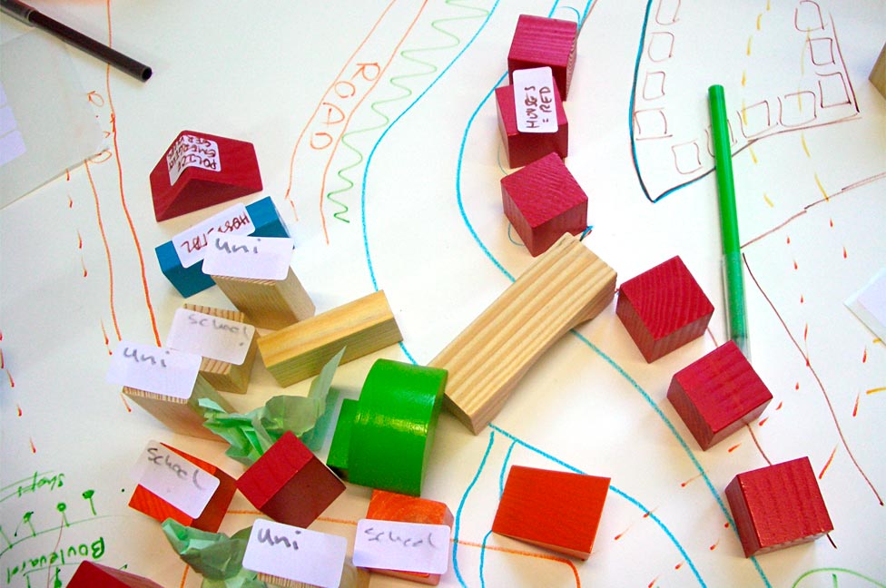 Colourful wooden blocks and a drawn map on paper, representing a planning or design activity